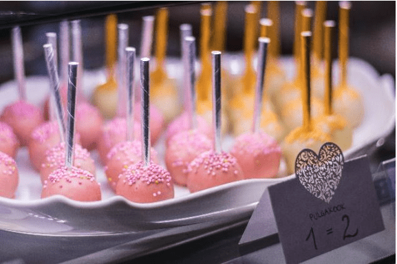 Pink and yellow pop cakes on stocks on white dish
